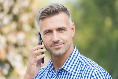 Telefonla yardım. Modern cihazlarla iletişim. Neşeli adam cep telefonuyla konuşuyor. Yakışıklı iş adamının saçları beyazlamış. Olgun adam her zaman çevrimiçi. çevik iş konsepti