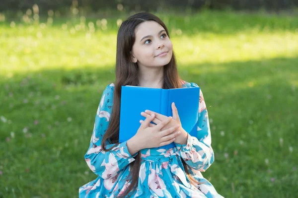 Niña relajante al aire libre con libro, concepto de tarea de la escuela —  Fotos de Stock