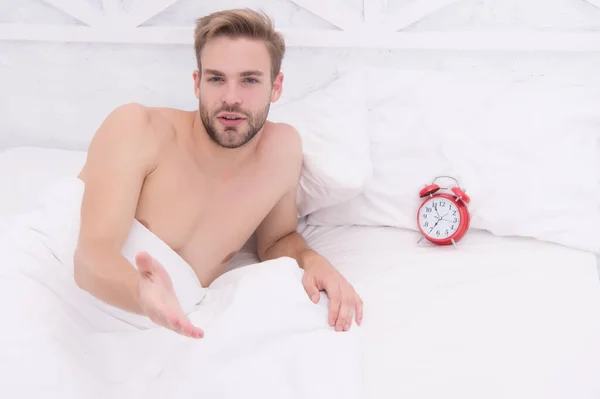 Adam uyuyan beyaz yatak örtüleri ve kırmızı alarm saati, sabah uyandırma konsepti. — Stok fotoğraf