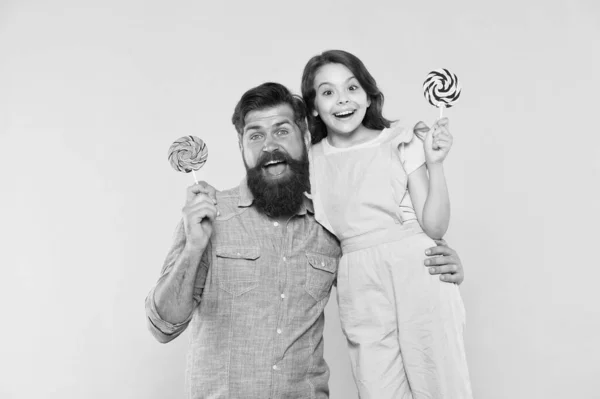 Papi cariñoso y niña comiendo piruleta. Vacaciones de verano. Felices fiestas. Dulce infancia. Cuando los niños parecen difíciles de complacer. Hija y padre comen dulces dulces. Barbudo hombre y lindo dulce bebé — Foto de Stock