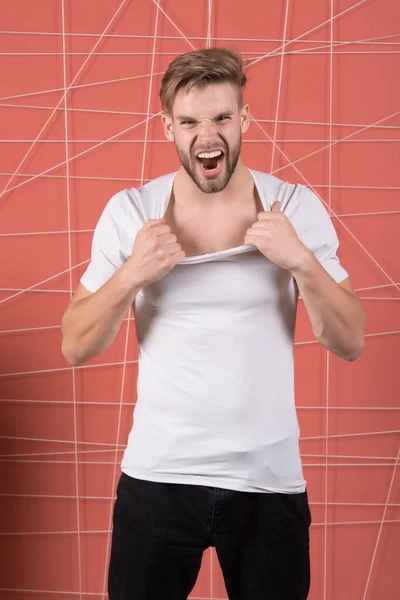 El hombre de moda tira del cuello de la camiseta con ira. Modelo de moda en estilo casual gritar sobre fondo rosa — Foto de Stock