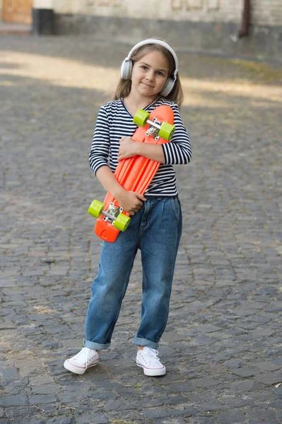 Petit enfant tenir penny skateboard écouter de la musique dans les écouteurs modernes été urbain en plein air, le sport — Photo