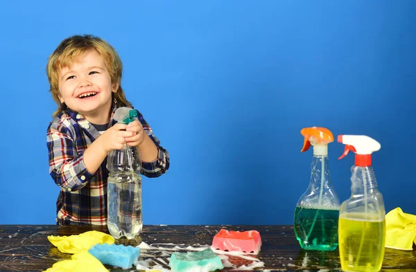 Kid with laughing face holds spray on table. — Stock Photo, Image
