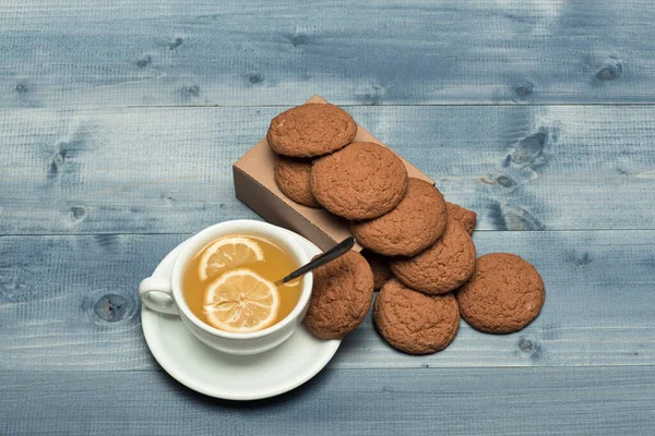 Koekjes op kartonnen doos bij thee op grijze houten ondergrond — Stockfoto