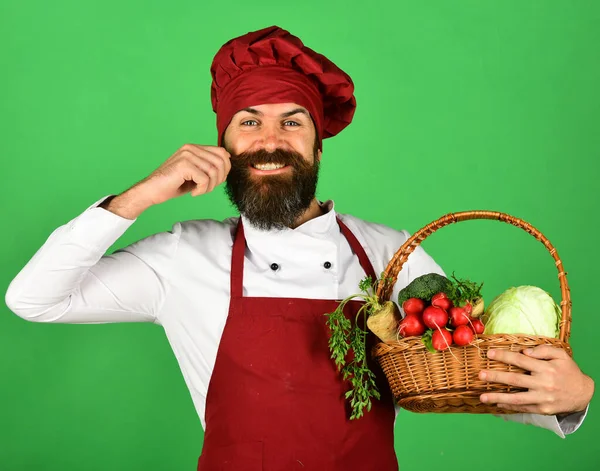 Şefin elinde lahana, turp, brokoli ve havuç var. Sakallı adam