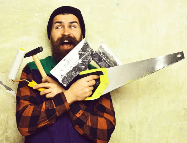 Бородатый человек держит различные строительные инструменты со счастливым лицом — стоковое фото
