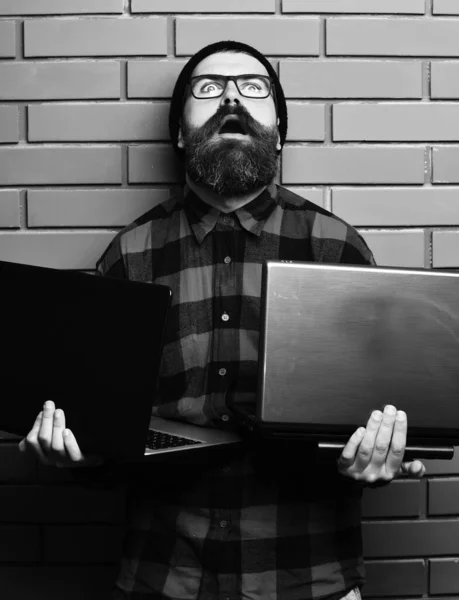 Skägg brutala kaukasiska hipster håller bärbara datorer på brun tegelvägg studio bakgrund — Stockfoto
