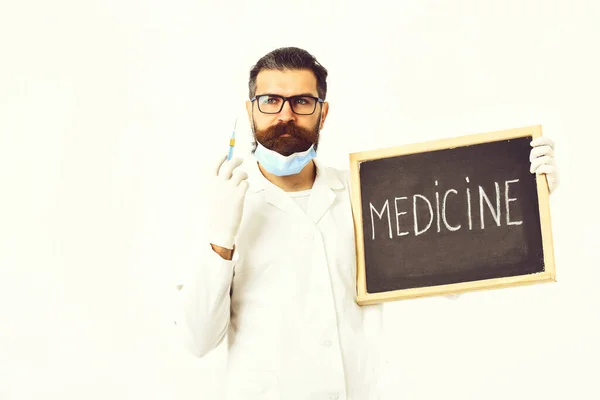 Médico caucasiano barbudo segurando seringa e papelão com inscrição em Medicina — Fotografia de Stock