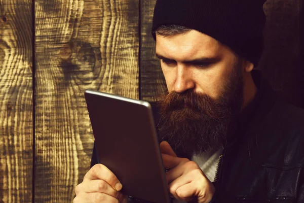 Kahverengi, eski, ahşap stüdyo arka planında tablet tutan Kafkasyalı vahşi hippi.