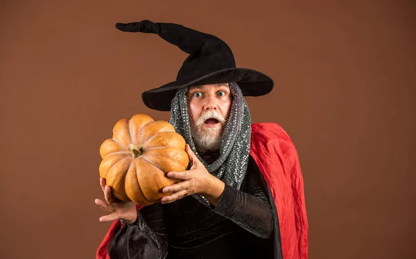 What a big surprise. happy halloween. Weird old grandfather with gray beard. ready to celebrate halloween. traditional food. Halloween man with pumpkin. Halloween party. witch man in hat and cloak — Stock Photo, Image