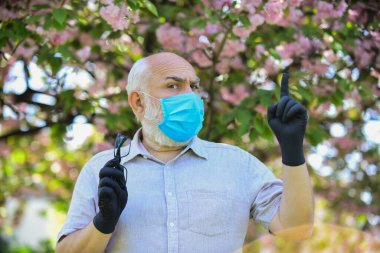 Enfeksiyonun yayılma riskini sınırla. Son sınıflar covid-19 hakkındaki yanlış bilgilere inanıyorlar. Dışarıda maskeli ve eldivenli kıdemli bir adam var. Enfeksiyon havada. Virüs enfeksiyonundan koru ve koru