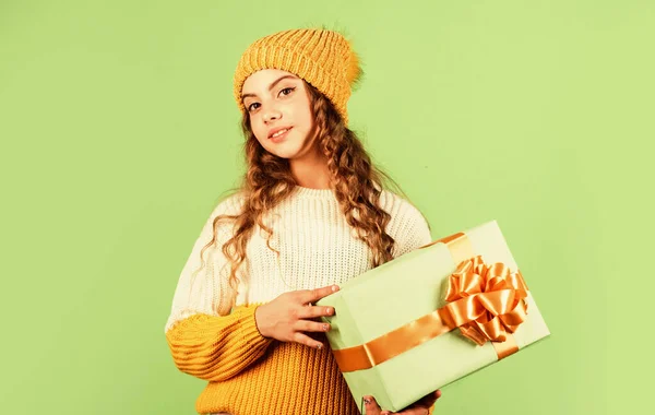 圣诞节来了新年快乐。圣诞礼品店出售。祝你圣诞快乐。寒假折扣。快乐的小女孩编织着帽子和毛衣。小孩拿着礼物盒绿色背景 — 图库照片