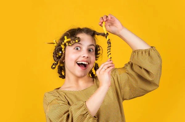 A desfrutar de cachos brilhantes. Condicionador de óleo de bálsamo para styling. Material de cabeleireiro. Moda e beleza. Salão de cabeleireiro menina pequena. Cabelo encaracolado de criança. Penteado para a festa. Belo cabelo saudável — Fotografia de Stock