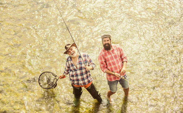 Collaborazione. due pescatori felici con canna da pesca e rete. padre e figlio pesca. bracconaggio. Campeggio sulla riva del lago. Pesca d'altura. amicizia. concetto di fuga rurale. hobby. natura selvaggia — Foto Stock