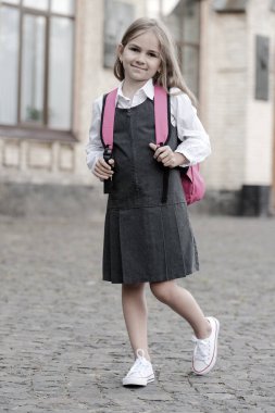 Şık ve zarif. Okul çantası taşıyan üniformalı küçük bir çocuk. Okul malzemelerine dönelim. Moda okulu kıyafeti. Üniforma. Resmi eğitim. 1 Eylül. Sonsuz bakış. Retro biçimi, vintage filtresi