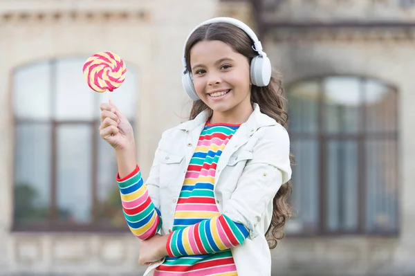 Menina fones de ouvido sem fio comer doces pirulito, conceito de férias de verão — Fotografia de Stock