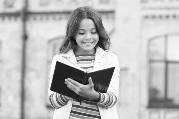 Mała dziewczynka trzyma książkę. Dziewczyna z wykształceniem książkowym. Książka z biblioteki. Robię notatki. Inspirujący poeta. Utalentowana uczennica. Dostęp do znacznie więcej niż tylko książki. Koncepcja wiedzy — Zdjęcie stockowe