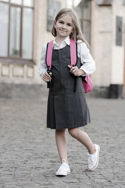Klassisk och elegant. En liten unge i uniform bär skolväska. Tillbaka till skolan. Mode skolkläder. Enhetlig klänning. Formell utbildning. 1 september. Tidlös blick. Retrostil, vintage filter — Stockfoto