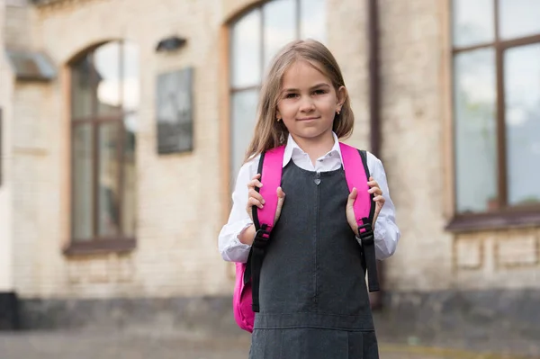 Маленька дитина в формальній модній формі несе шкільну сумку на відкритому повітрі, навчаючись — стокове фото