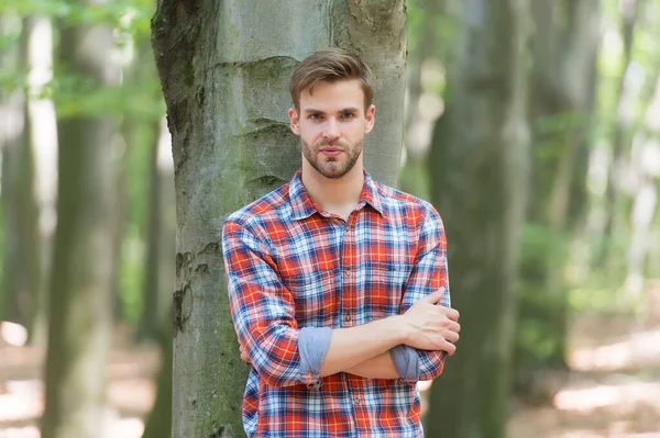 Junger Mann in Baumnähe trägt kariertes Hemd, lässige Mode — Stockfoto