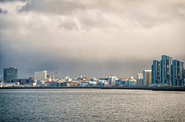Reykjavik paisagem marinha céu nublado dramático. Cidade na costa marítima Islândia. Conceito de paisagem marinha escandinava. Superfície de água calma e cidade com edifícios altos arquitetura moderna. Cidade escandinava à beira-mar — Fotografia de Stock