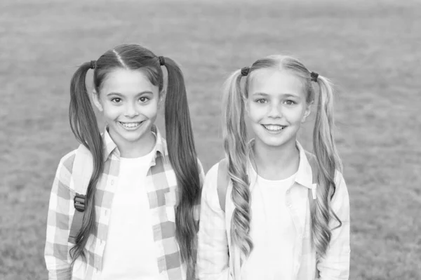 Septiembre. Se acabaron las vacaciones. De vuelta a la escuela. Colegialas lindas con colas de caballo largas. Fin del año escolar. Alegre colegialas inteligentes. Colegialas felices al aire libre. Colegialas pequeñas con mochilas —  Fotos de Stock