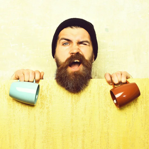 Barbudo brutal hipster caucásico con hoja de papel y tazas —  Fotos de Stock