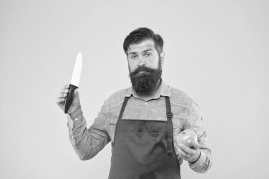 Yemek pişirmek. Kırmızı önlüklü profesyonel şef. Yemek pişirmek onun hobisi. Aşçı üniformalı sakallı adam. Kendine güvenen erkek hizmetçi domates hazırlar. Olgun adam elinde bıçak ve sebze tutuyor. Taze salata yapıyorum.