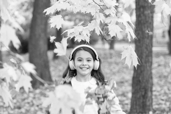 Křupavý podzimní vzduch. Šťastné malé dítě úsměv poslouchat hudbu na podzim dne. Holčička si hraje na čerstvém vzduchu na podzimní krajině. Cítit svěží vzduch a cítit listí — Stock fotografie
