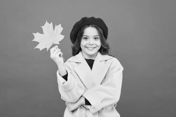 Herbstmode. glückliches kleines Mädchen mit Ahornblatt. Herbstliche Kindermode. Pariser Mädchen in französischem Barett und gelbem Mantel. Herbstzeit. Schulzeit. Kinderglück. Umgestürzte Blätter — Stockfoto