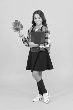 İlgi ve ilgi, okul dönüşü. Mutlu küçük kız sonbaharda okula geri dönüyor. Sevimli ilkokul çocuğu kitap ve sonbahar yapraklarını tutuyor. Yeni okul yılı. Başla. 1 Eylül