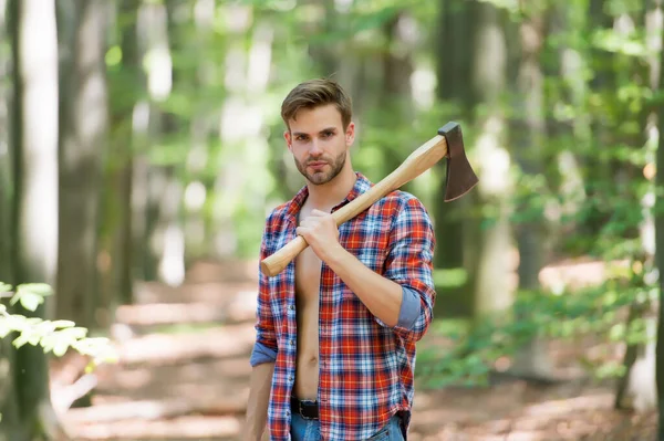 Homem bonito segurar machado na floresta, atividade. — Fotografia de Stock