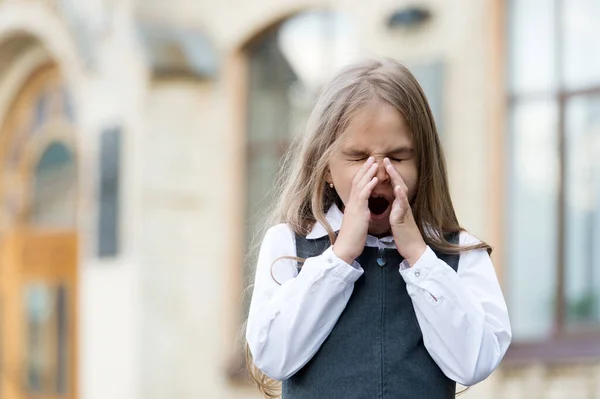 Pequeño niño con el pelo rubio con uniforme escolar dan bostezos largos en el patio de la escuela, mañana — Foto de Stock