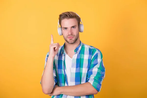 Handsome man wear headphones keeping finger raised yellow background, idea — Stock Photo, Image