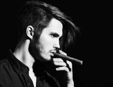 Ciddi sakallı adam puro içiyor.