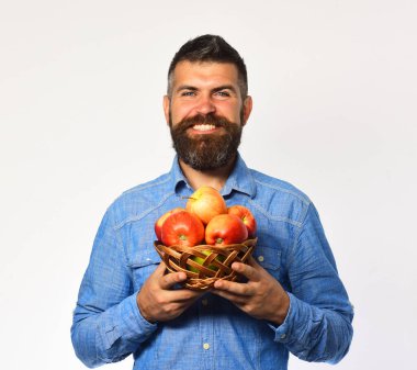 Sakallı adam elinde meyve dolu hasır kasesi tutuyor.