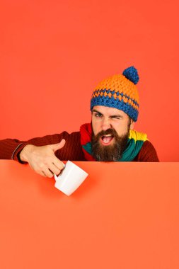 Sakallı bir adam beyaz çay fincanını tutuyor..