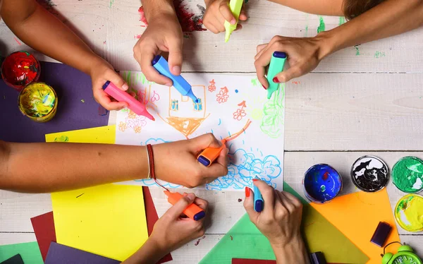 Eller renkli kalemleri tutar ve çocukların resimlerini çizer.