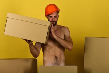 Elinde karton kutuyla çırılçıplak duran kasklı adam.