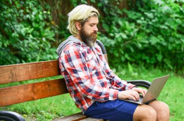 İnternetten alışveriş. İnternette çalışıyorum. Hippi parkta ilham kaynağı oldu. Temiz hava. Gezici internet. İstediğin yerde çalışabilirsin. Çevik iş. Sakallı adam park doğasında bankta oturuyor. Çalış ve rahatla