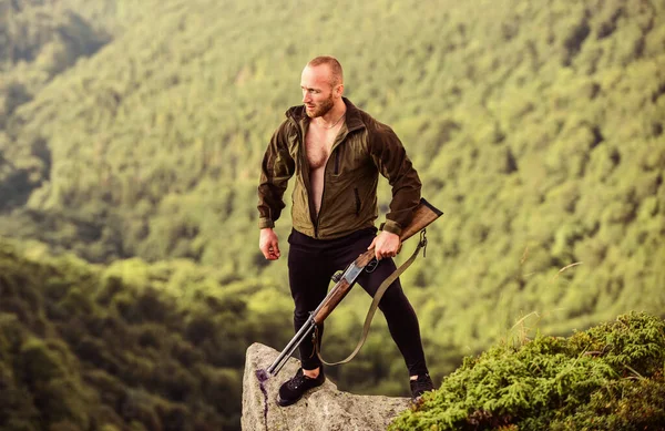 Kaçak avcı uçurumun kenarında duruyor. Kaçak avlanma kavramı. Adam vahşi kaçak avcı, silah ve doğal manzara. Avcı kaçak avcı kurban arıyor. Tüfek doğası olan bir avcı. Yasadışı avlanma
