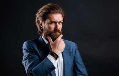 Pahalı takım elbiseli yakışıklı ve başarılı bir adam. Elli saati olan tişörtlü adam. Takım elbiseli başarılı bir adam. İş adamı takım elbise giyer. Resmi ofis hayatı. Ciddi sakallı adam.