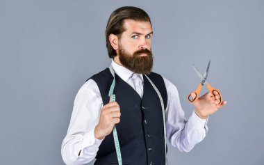 Kendine güvenen bir terzi. Model için özel dikim takım elbise. İş gömleği mağazada mezura ve makasla dikiliyor. Beyaz gömlekli yakışıklı terzi. Antika mobilyalarla muhteşem bir atölye.