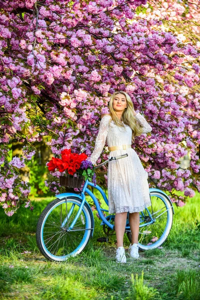 Styl wiosenny. różowy kwiat wiśni. dziewczyna niesie kwiaty w rowerze retro. wiosna ładna kobieta w sukience. Dziewczyna z klasycznym rowerem. Kwitnące drzewo sakura. letnia moda i piękno. pani spacer w parku — Zdjęcie stockowe