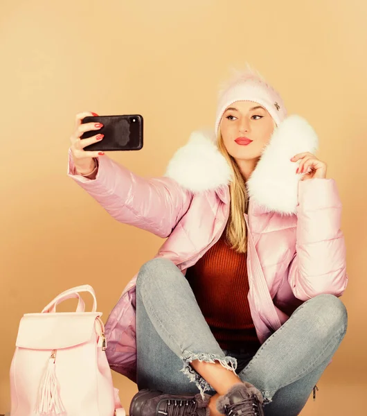 Ragazza in cappotto soffiato fare selfie. moda eco-pelliccia. abbigliamento invernale caldo. selfie telefonico. influenza e stagione fredda. Borsa in pelle moda. Cappello donna in berretto con zaino. buone vacanze invernali. blogger web — Foto Stock