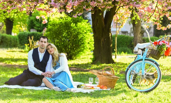 Par i kärlek dricka vin under romantisk middag i parken. picknick par förälskade på vintage cykel. Familjeförhållande och vänskap. sommarsemester resa. flicka och man under sakura — Stockfoto
