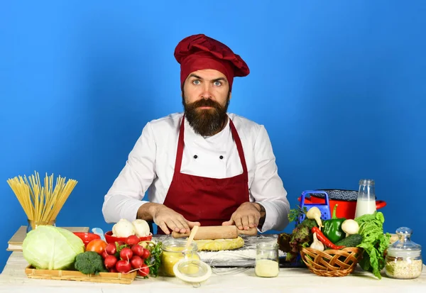 Cook med allvarligt ansikte i vinröda uniformsrullar deg — Stockfoto