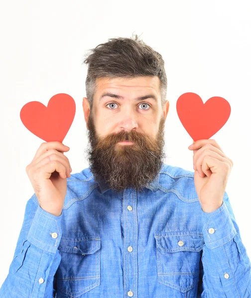 Чоловік з бородою з спокійним обличчям тримає червоні паперові серця — стокове фото