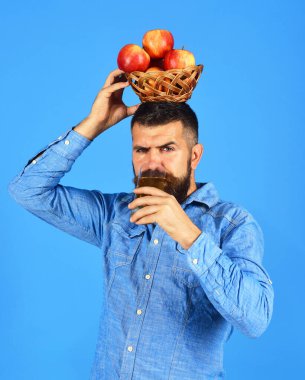 Sakallı adam elinde meyve ve meyve suyu dolu hasır bir kase tutuyor.