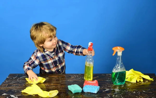 Kid wiping table with yellow rag and holds spray. — Stock Photo, Image